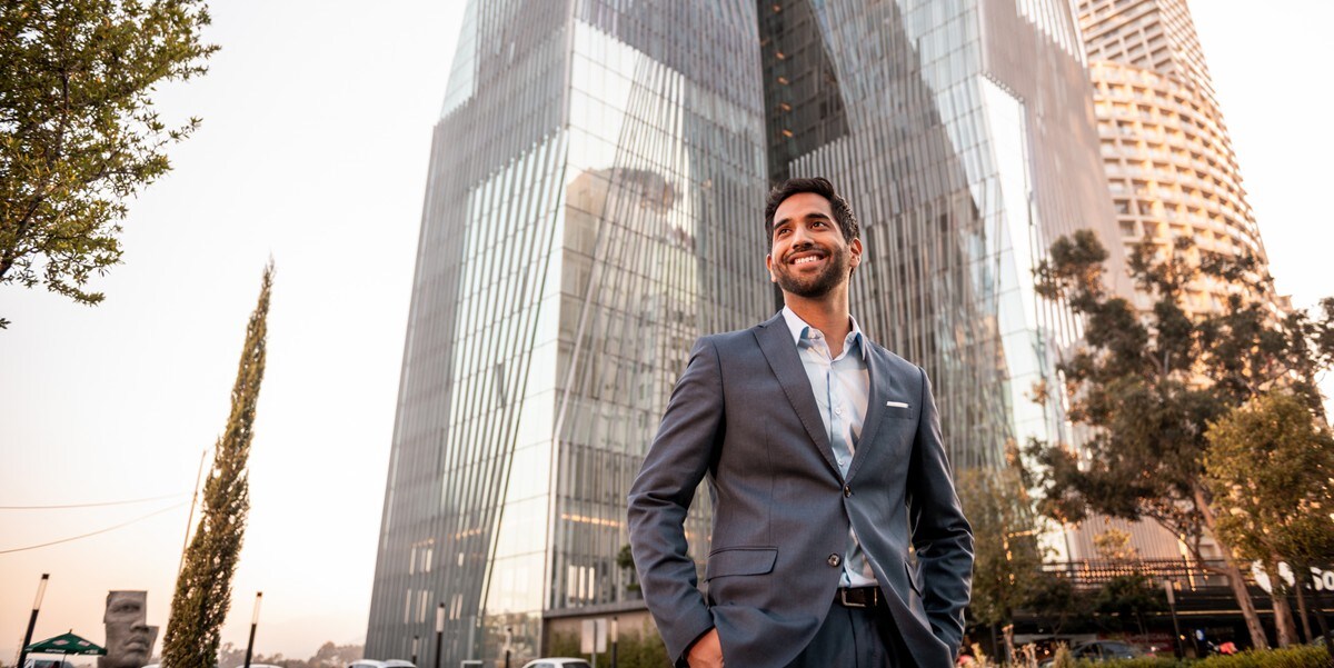professional man smiling, standing outside office building