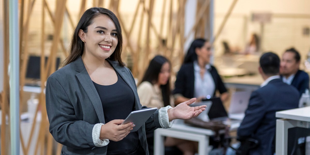 professional woman smiling, colleagues in the background at a table