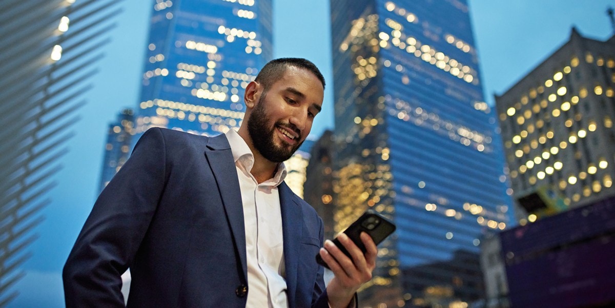 man standing outside of building, looking down at cell phone