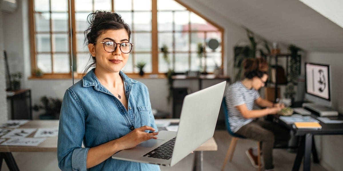 woman in office, holding laptop