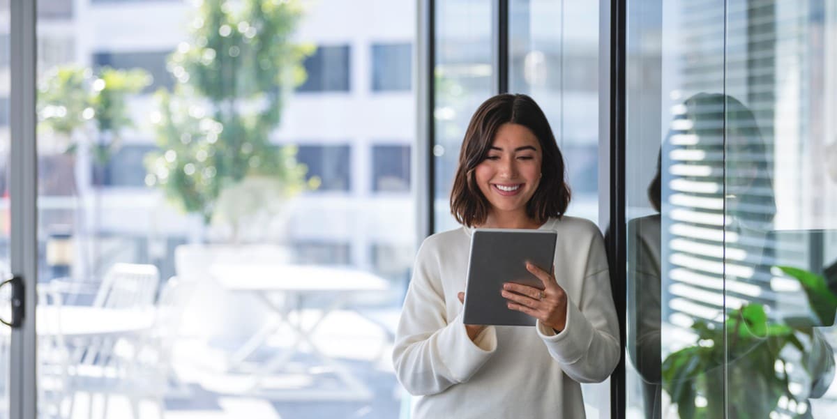 woman reading a tablet, standing next to building