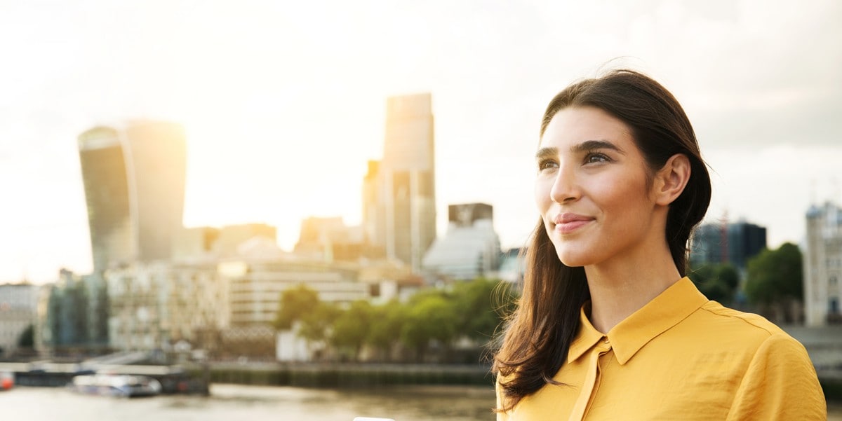 smiling woman standing outside, in front of city skyline