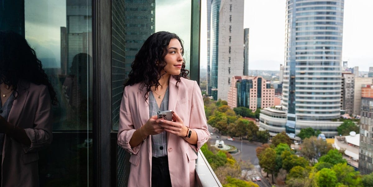 woman standing outside on balcony, holding cell phone