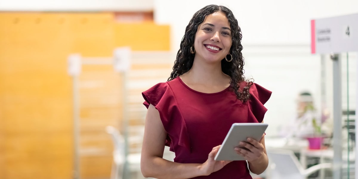 woman in office, holding tablet, smiling