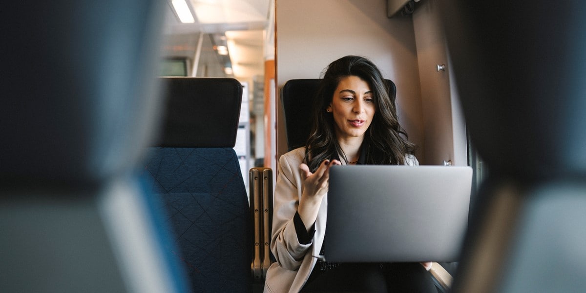 traveler sitting on a train, using laptop 