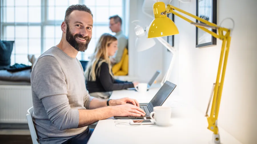 team working at desk with man looking at camera